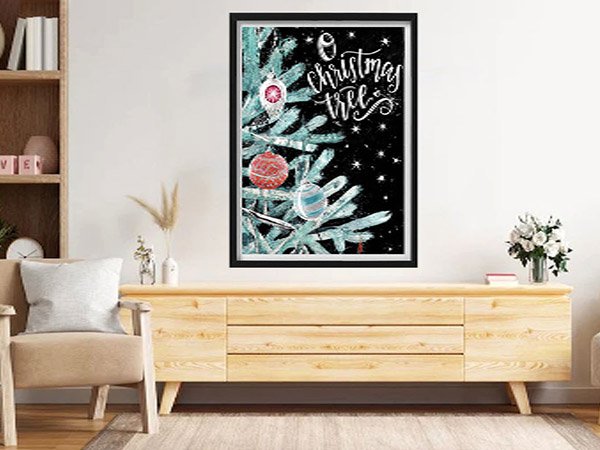 Framed 5D Christmas tree diamond painting kit with ornaments on a black background, displayed above a wooden credenza.
