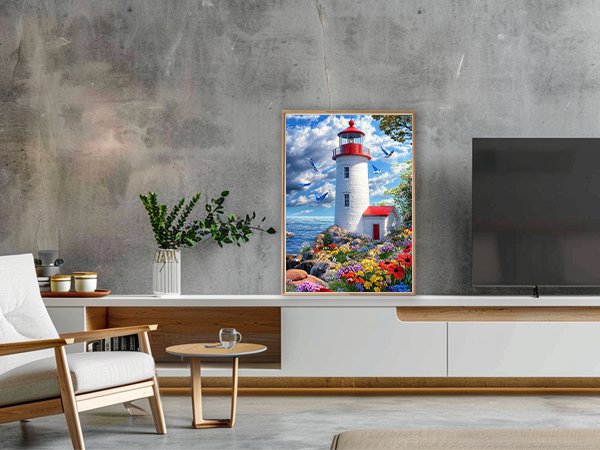 Diamond painting kit of a lighthouse on a rocky shore with colorful flowers and birds in the sky, framed and displayed in a living room.
