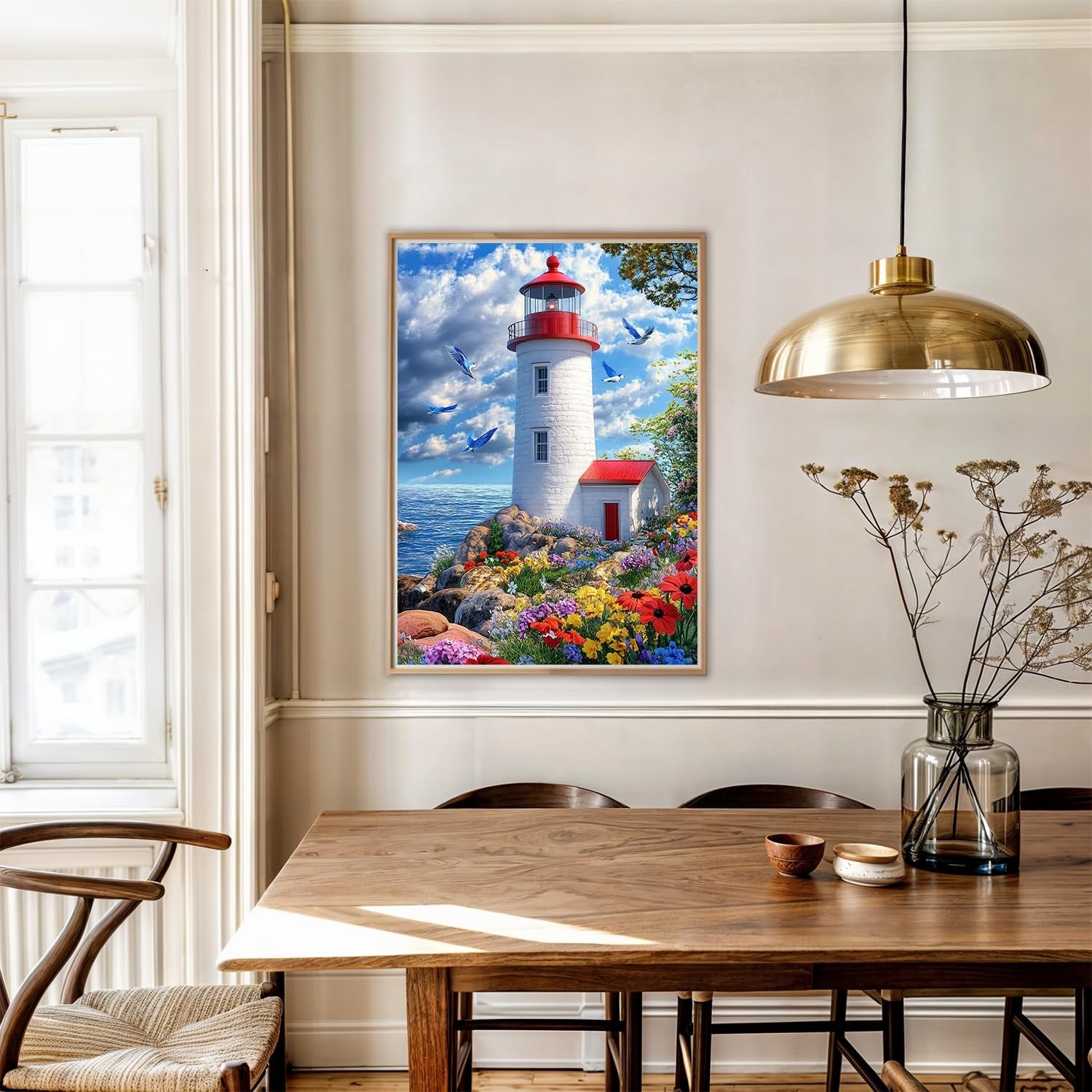 Diamond painting kit featuring a lighthouse on a rocky shore with colorful flowers and birds in the sky, framed and hanging on a wall above a dining table.