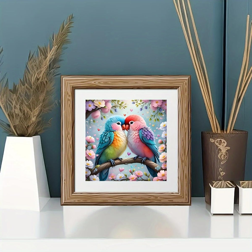 Framed diamond painting of two lovebirds on a branch surrounded by pink flowers.