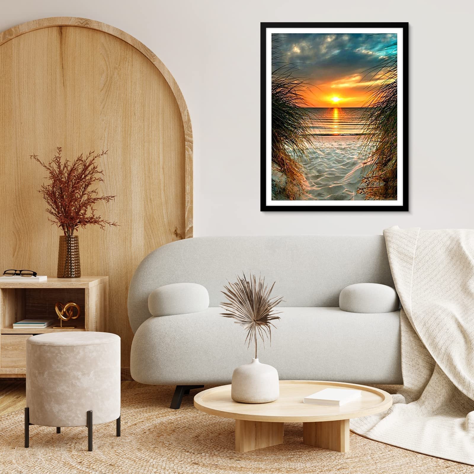 Framed diamond painting of a beach sunset viewed through tall grass, displayed in a living room setting.