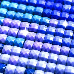 Close-up of a diamond painting canvas with rows of blue and purple faceted resin gems.