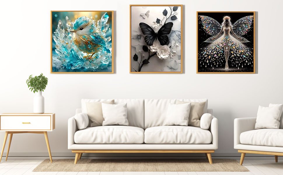 Three framed diamond paintings displayed on a white wall above a sofa: a blue bird, a black butterfly, and a fairy.