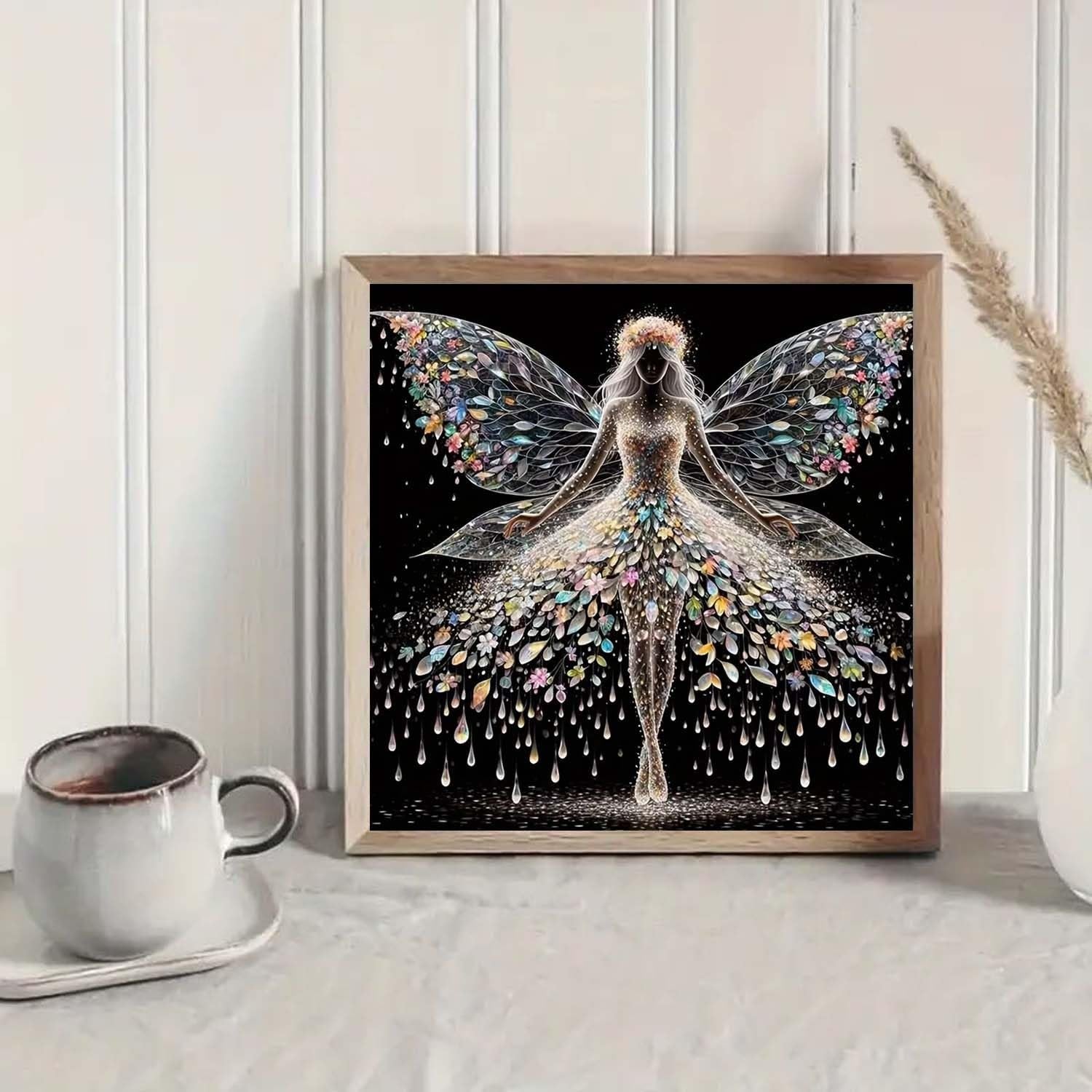 Diamond painting kit featuring a colourful angel wings fairy design, framed and displayed on a shelf with a coffee cup.