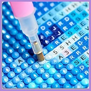 Diamond painting kit with pink applicator tool placing blue diamond onto canvas with printed letters