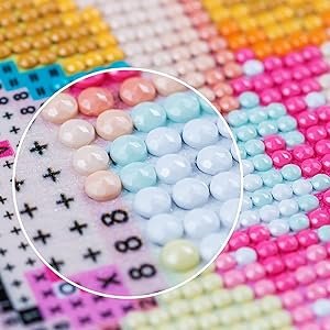 Close-up of 5D diamond painting kit with cross and lily flowers pattern, showing colorful round drills and printed symbols.