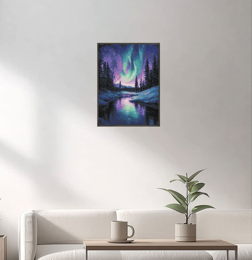 Diamond painting of the Aurora Borealis over a snowy forest and lake, framed and hanging on a wall above a sofa.