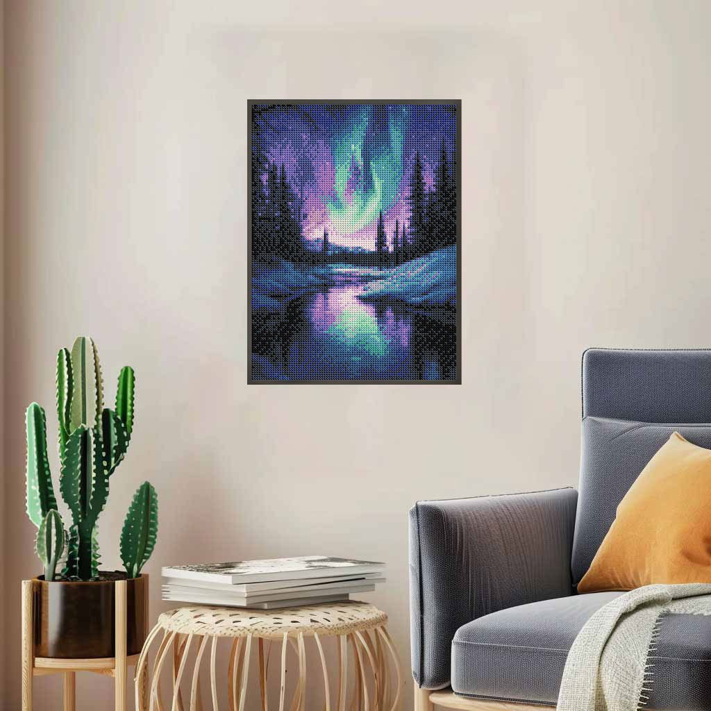 Diamond painting kit depicting the Aurora Borealis over a reflective river and snow-covered trees, framed and hung on a wall.