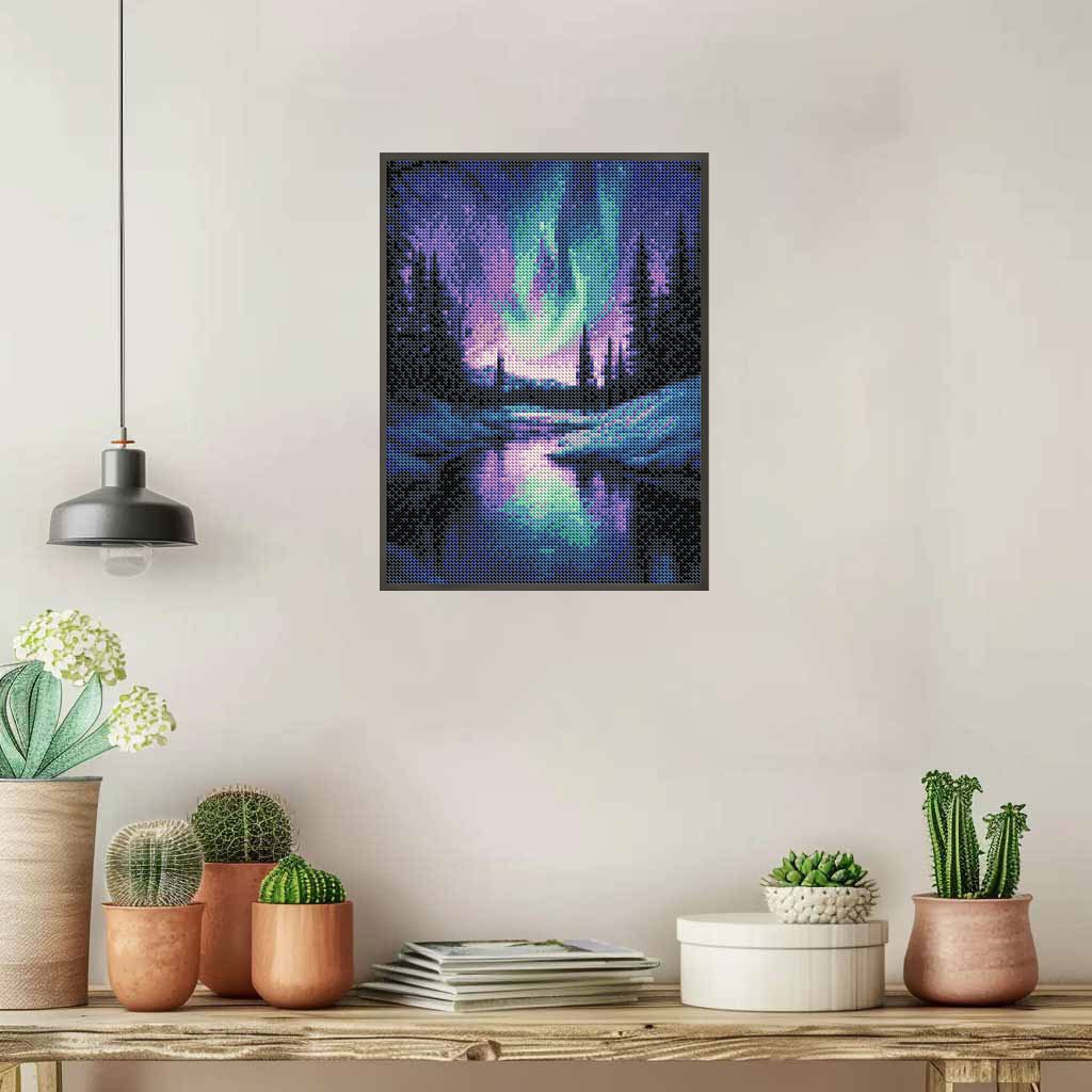 Diamond painting kit depicting the Aurora Borealis over a snowy forest and reflective lake, framed and hung on a wall.