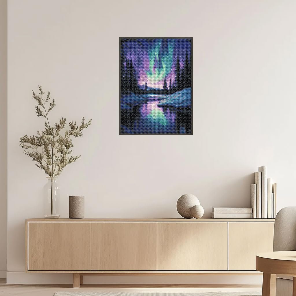 Diamond painting of the Aurora Borealis over a snowy forest and lake, framed and hanging on a wall.