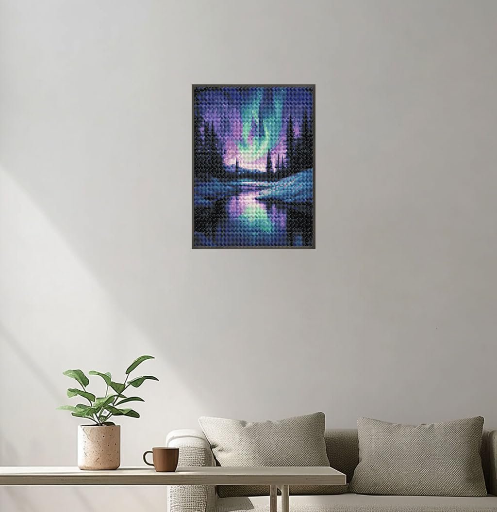 Diamond painting of Aurora Borealis over a snowy forest and lake, framed and hanging on a wall above a couch.