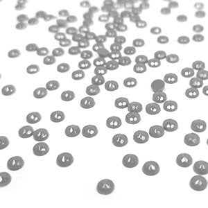Scattered round diamond painting beads on a white surface, close-up shot with shallow depth of field.