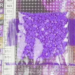 Bag of purple diamond painting drills with a grid of symbols and letters in the background.