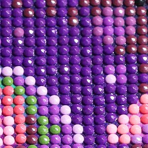 Close-up of a 5D diamond painting kit with a retro witch design, showing rows of colorful round drills in purple, pink, and green.