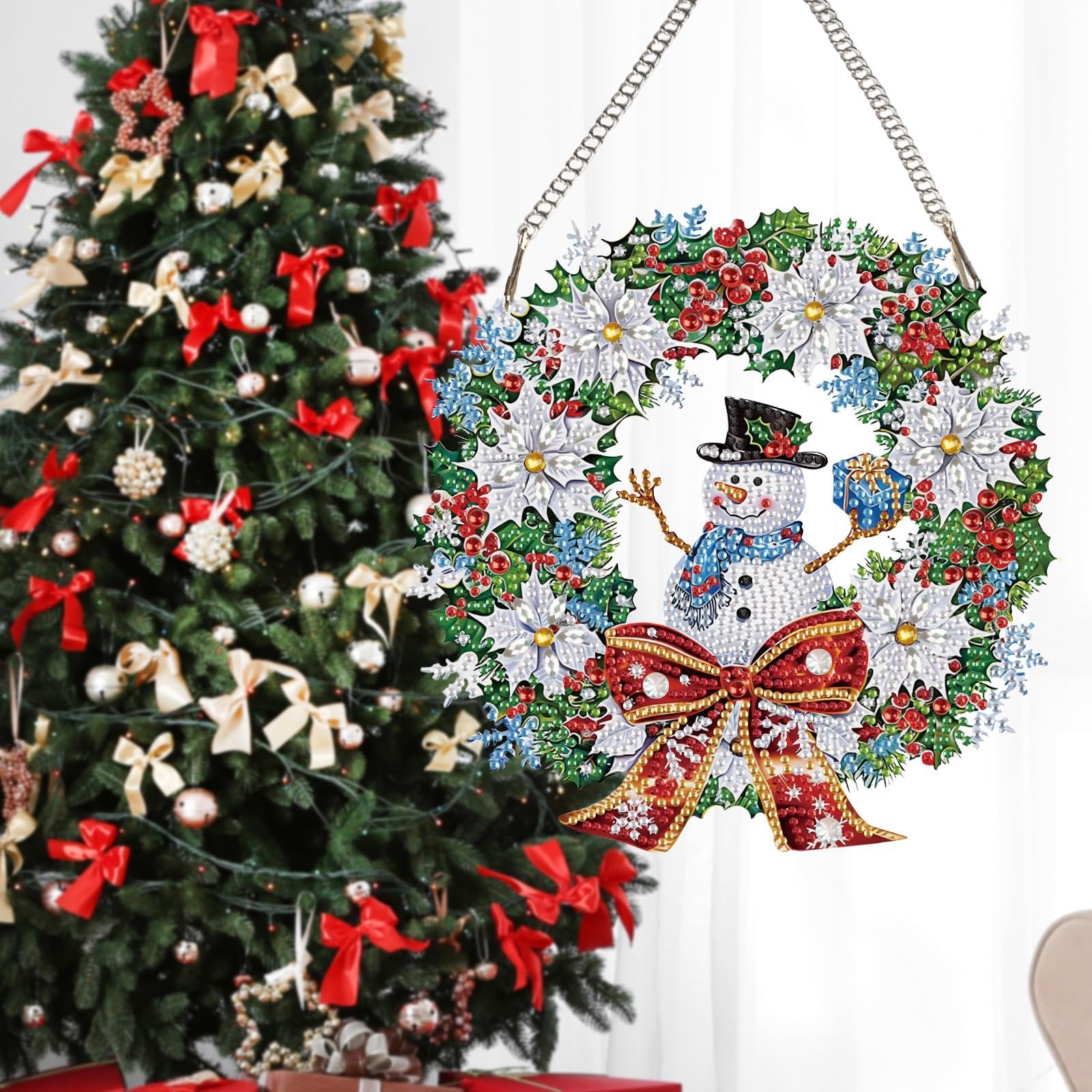 Diamond painting snowman wreath ornament hanging in front of a decorated Christmas tree