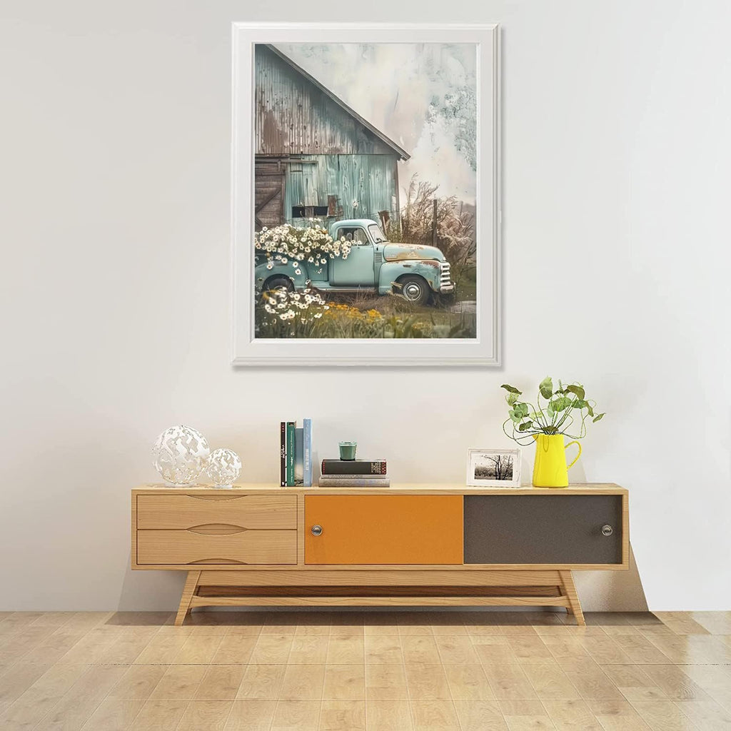Framed diamond painting of a vintage blue truck with flowers parked by a rustic barn.