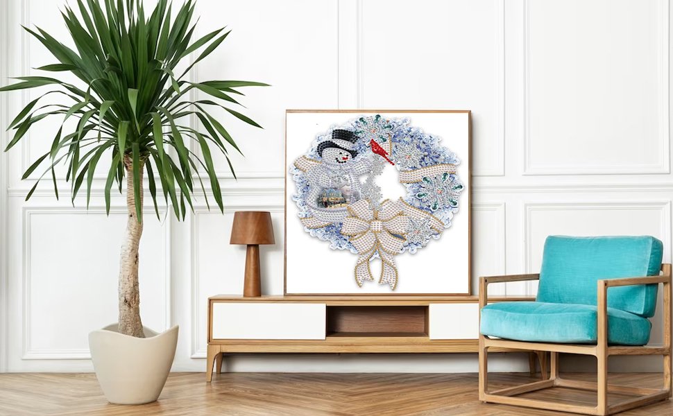 Diamond painting kit of a Christmas wreath with a snowman and bow, displayed on a wall above a credenza.