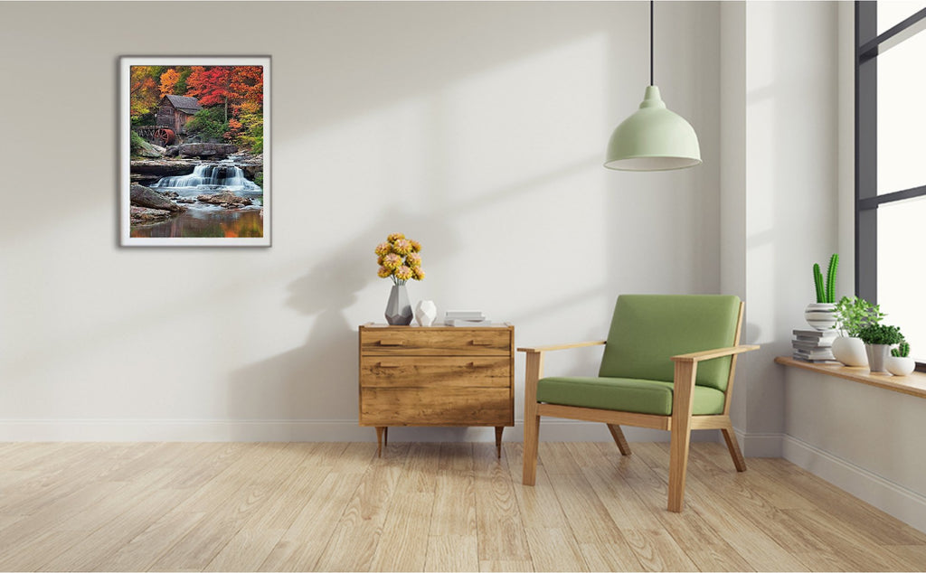 Framed diamond painting of a waterfall and old mill in autumn forest, displayed on a wall above a wooden cabinet.