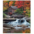 Waterfall flowing past a rustic wooden mill with a water wheel in autumn forest