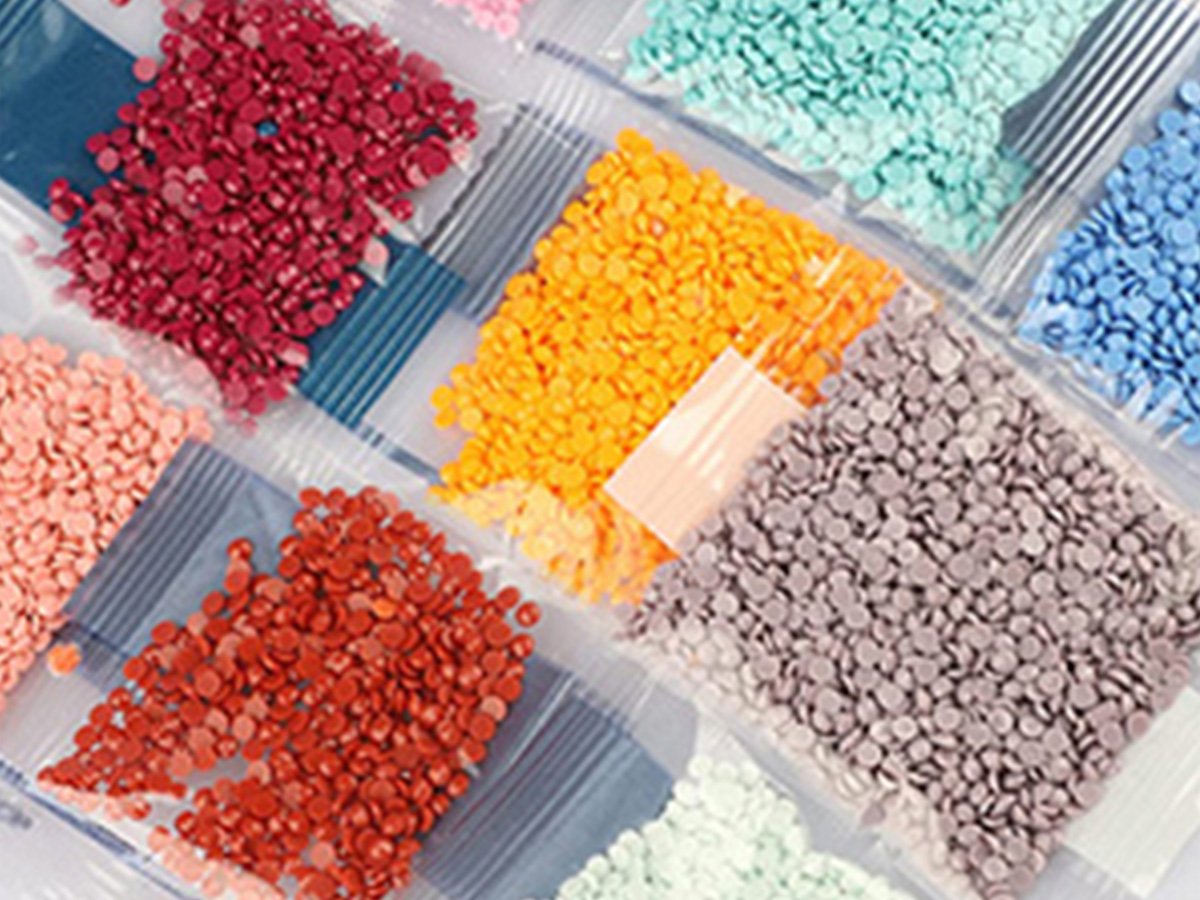 Assortment of small, colorful round diamonds for diamond art painting kits, packaged in clear plastic bags.