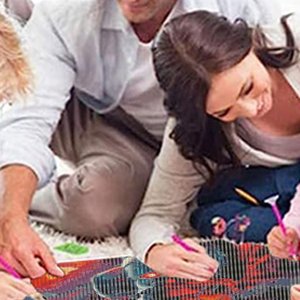 Family working on a diamond painting kit on the floor, using pink diamond art pens.