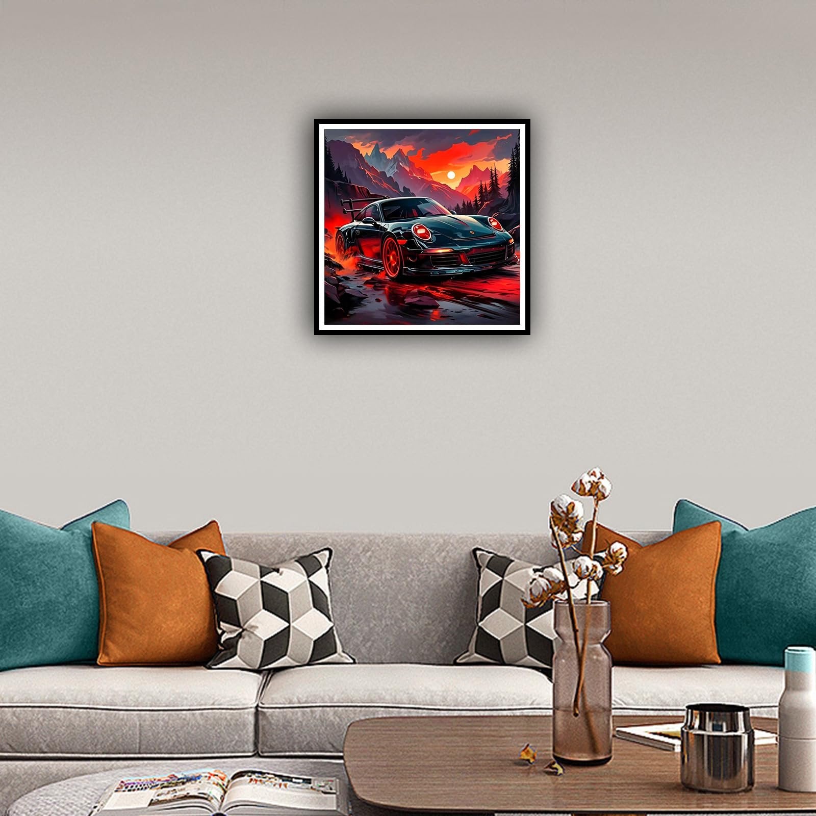 Framed diamond art painting of a black sports car driving on a wet road with mountains and sunset in background, displayed on a wall above a sofa.