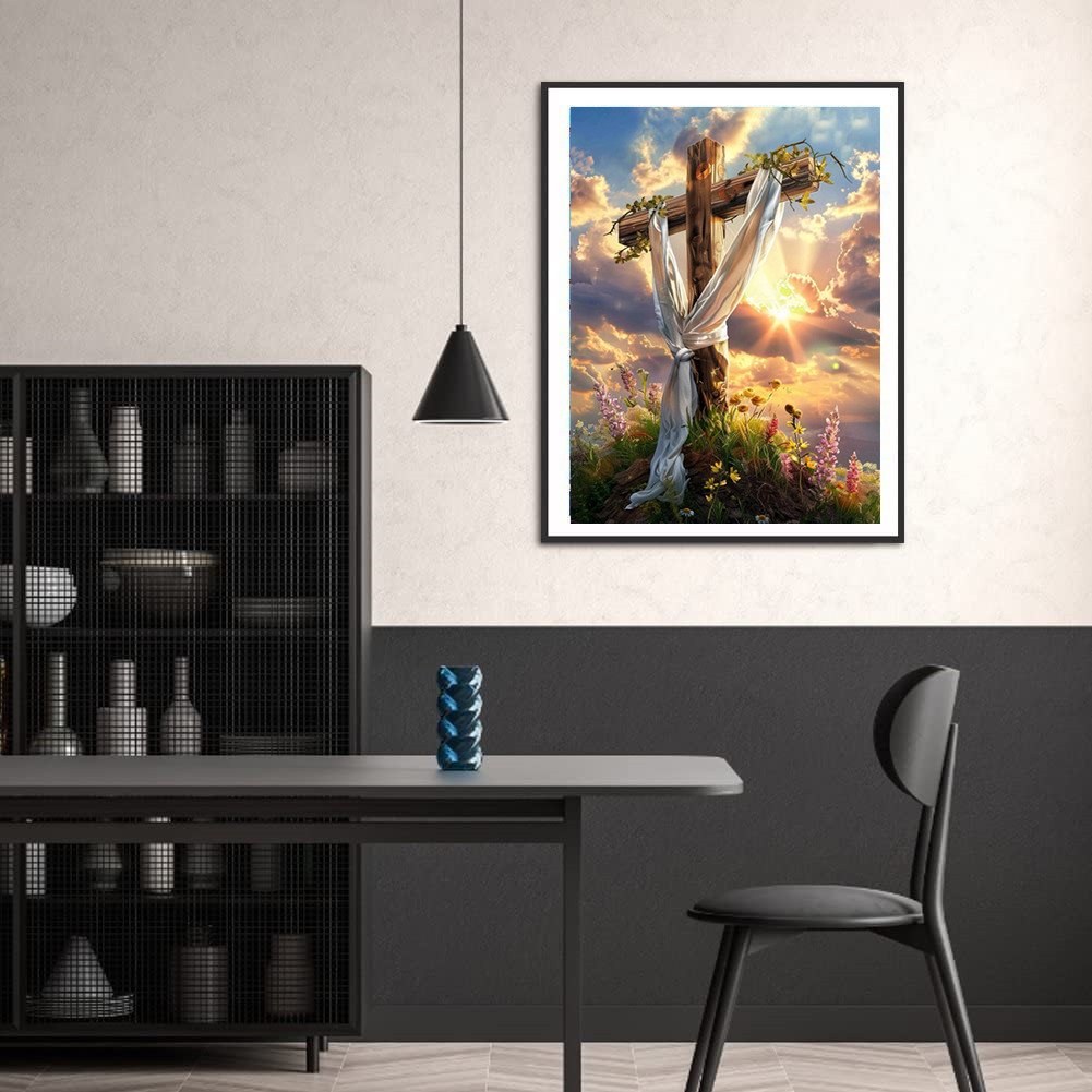 Diamond painting kit featuring a wooden cross draped with white cloth against a sunset sky with flowers.