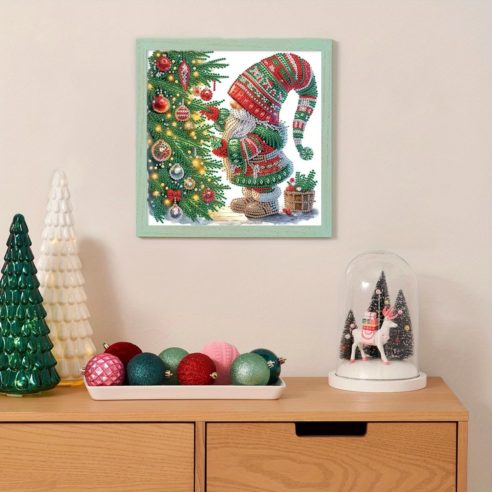 Diamond painting kit of a gnome by a Christmas tree, displayed on a shelf with festive decorations.