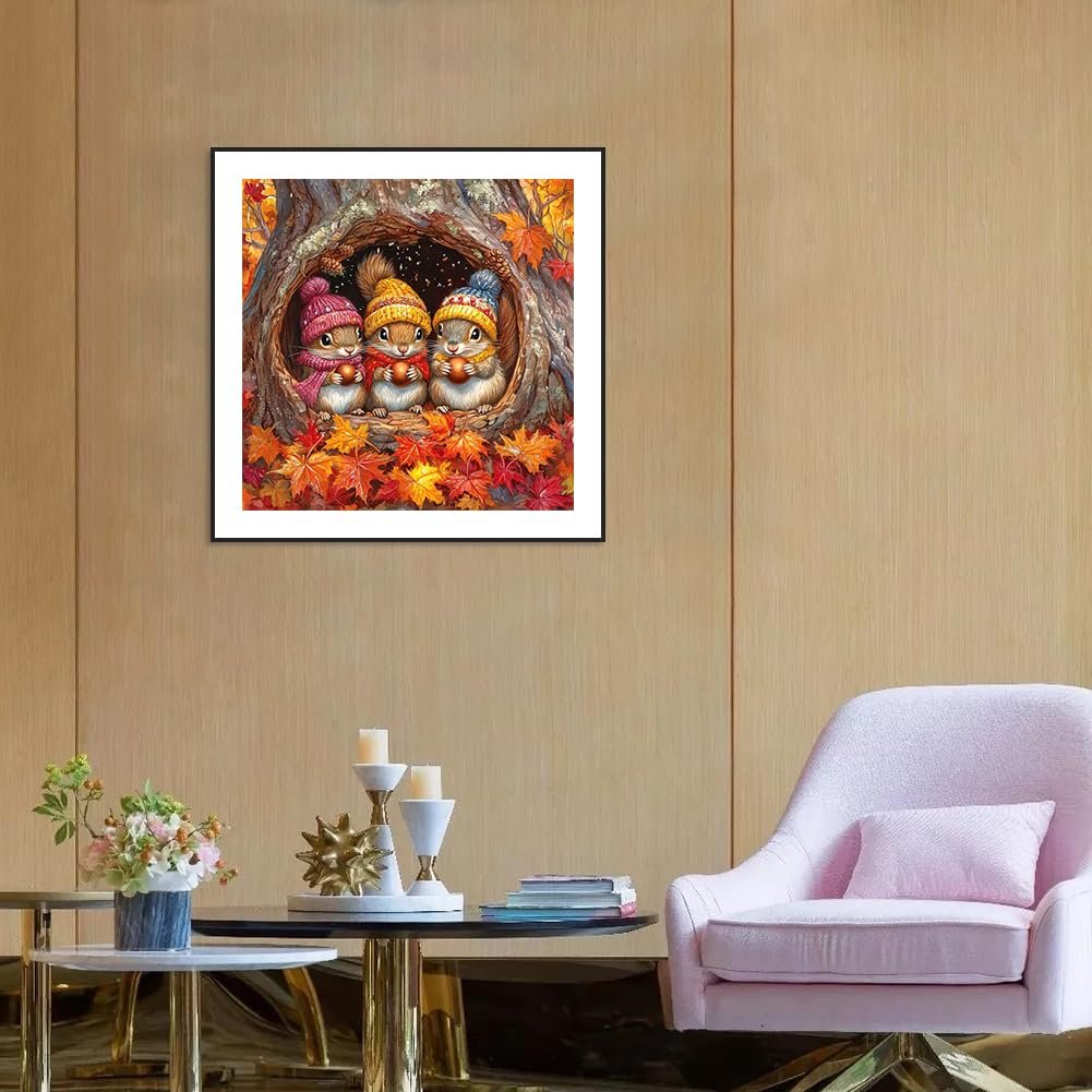 Diamond painting of three squirrels in beanies holding acorns inside a tree hollow surrounded by autumn leaves.
