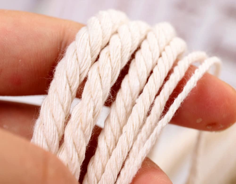 Close-up of beige natural cotton macrame cord being held by fingers, showing its twisted texture.