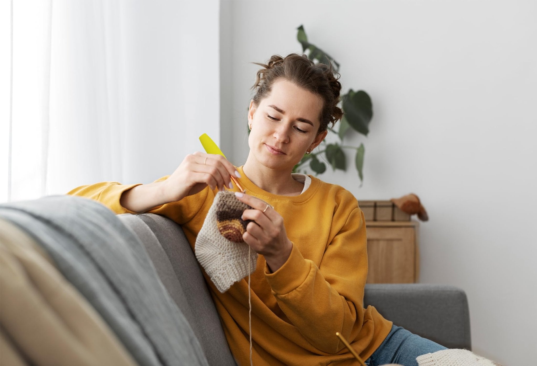 Woman crocheting with ergonomic foam handle crochet hook on a couch