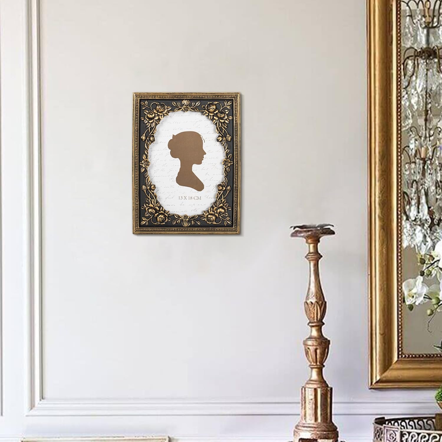 Vintage black and gold ornate picture frame with floral details hanging on a wall, showing a silhouette of a woman's profile.