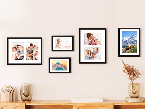 Gallery wall display of five black picture frames with family photos and a landscape on a light wall.