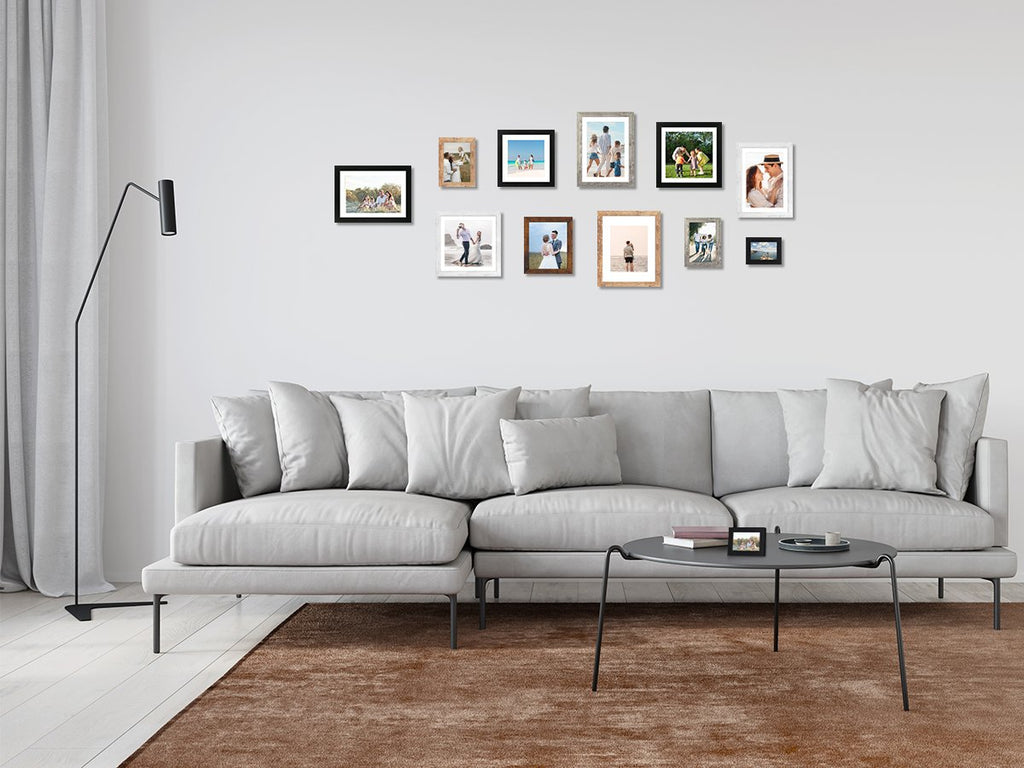 Gallery wall of assorted picture frames above a sectional sofa and coffee table in a living room.