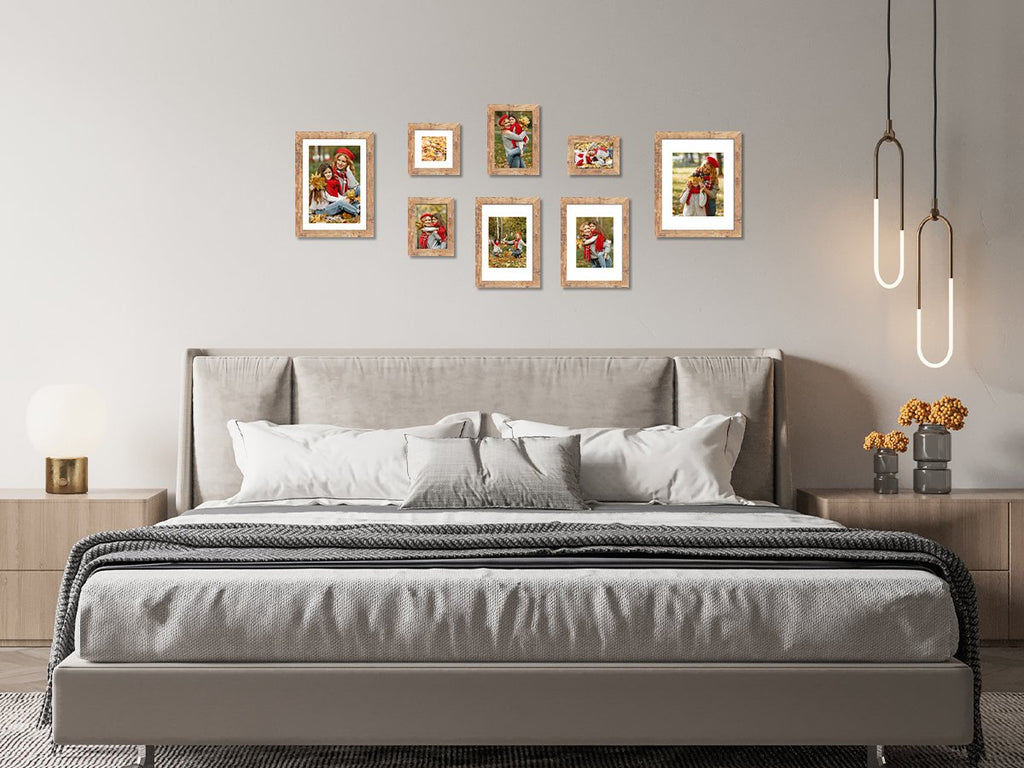 Gallery wall of seven rustic brown picture frames displaying family photos above a bed in a bedroom setting.