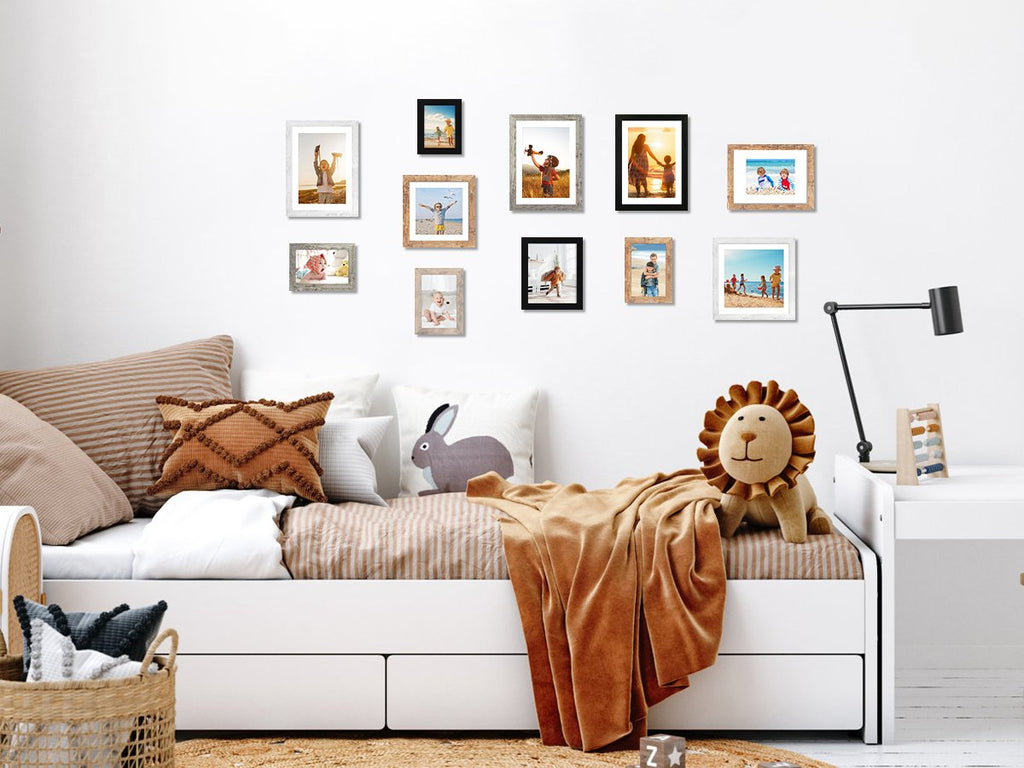 Gallery wall of ten picture frames above a child's bed with a lion plush and blanket.