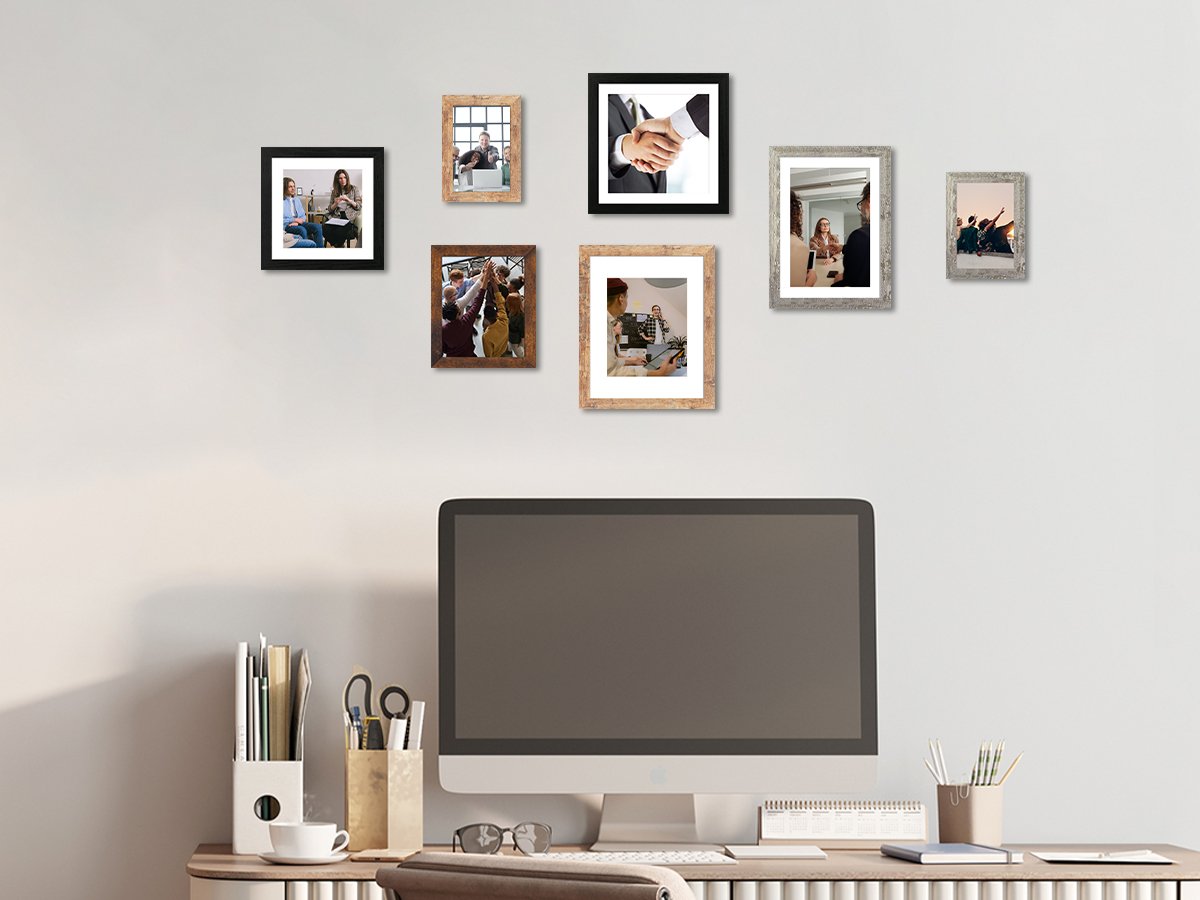 Office desk with a computer and a wall display of seven framed photos showing business and casual scenes.