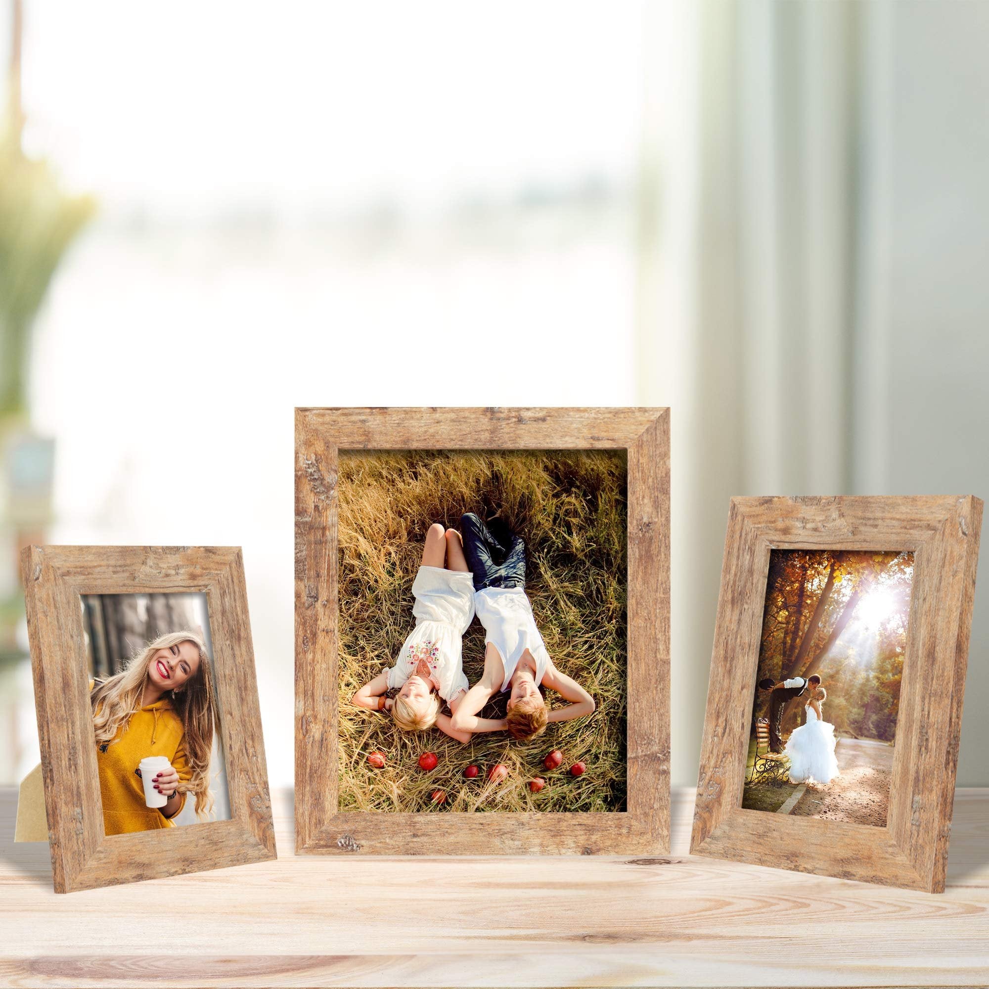 Three rustic brown picture frames displaying photos of people on a wooden surface with a blurred background.