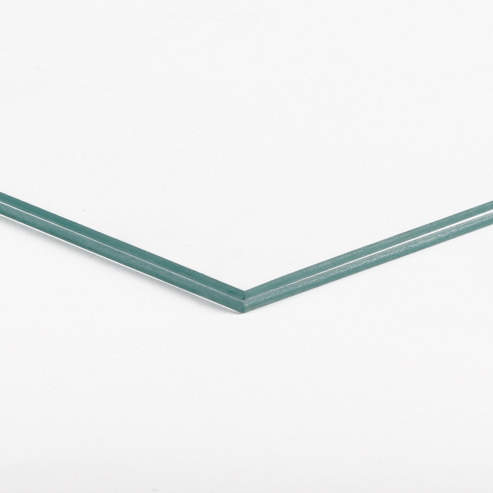 Close-up of two stacked clear glass panes with teal-tinted edges on a white background.