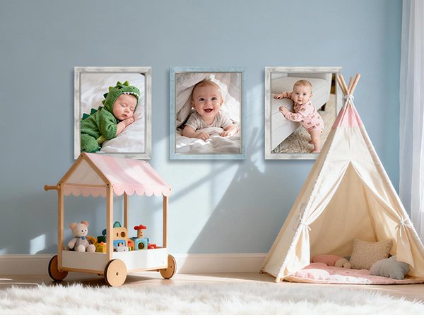 Three framed photos of babies displayed on a light blue wall above a toy cart and teepee.