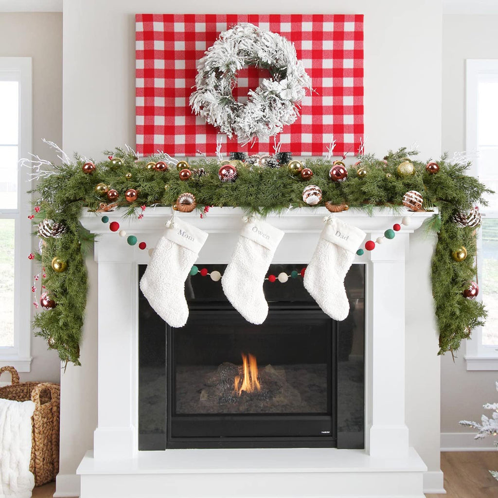 Christmas garland with red berries and pine cones draped over a fireplace with stockings hanging