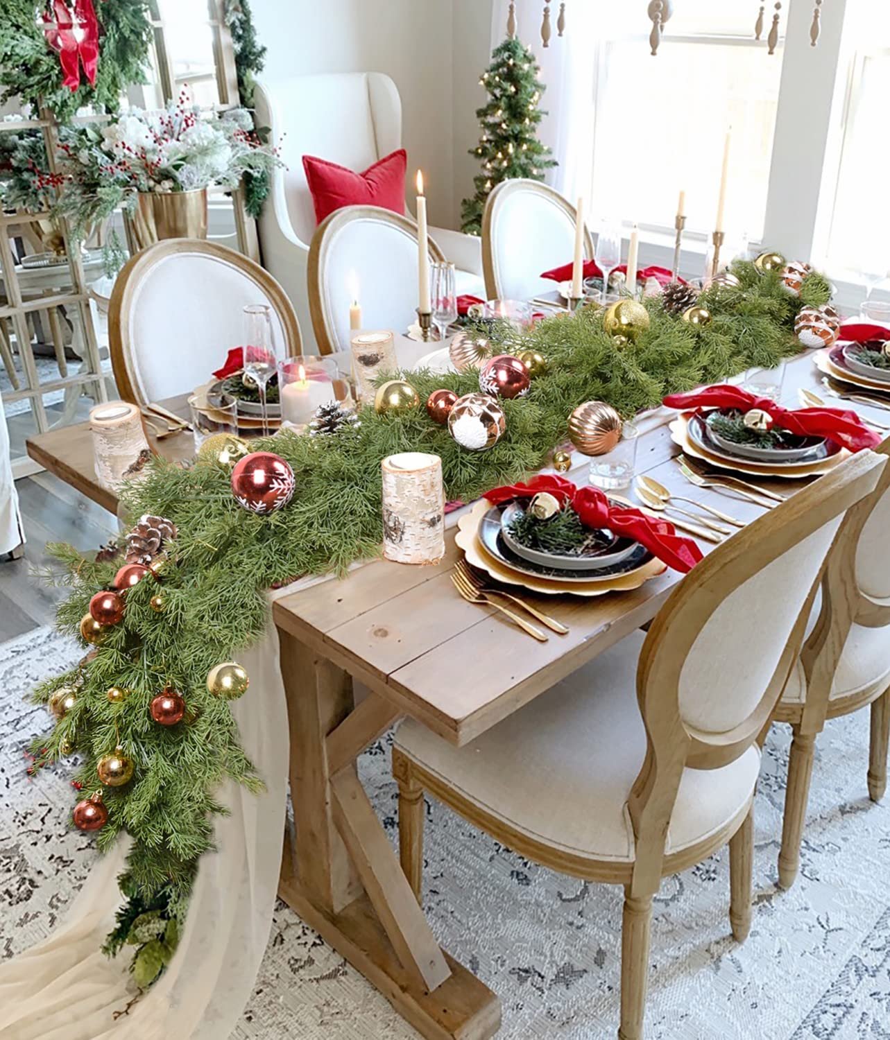 Christmas garland with red berries and pine cones draped across a dining table set for a meal.