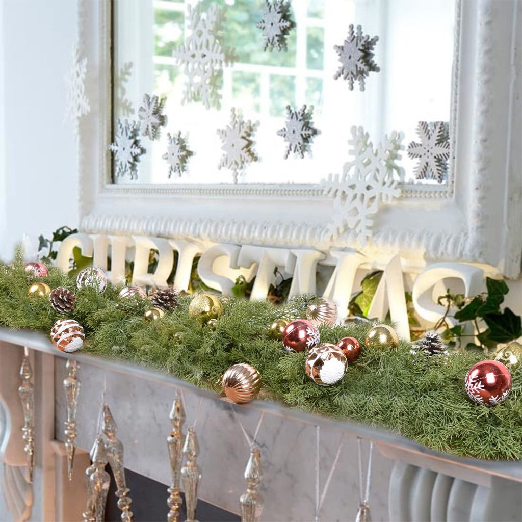 Artificial pine Christmas garland with red berries, pine cones, and ornaments on a mantlepiece.