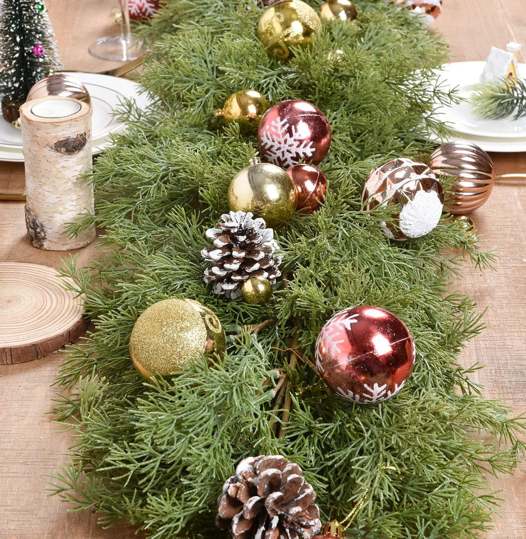 Artificial pine Christmas garland with gold and red ornaments and pine cones on a wooden table
