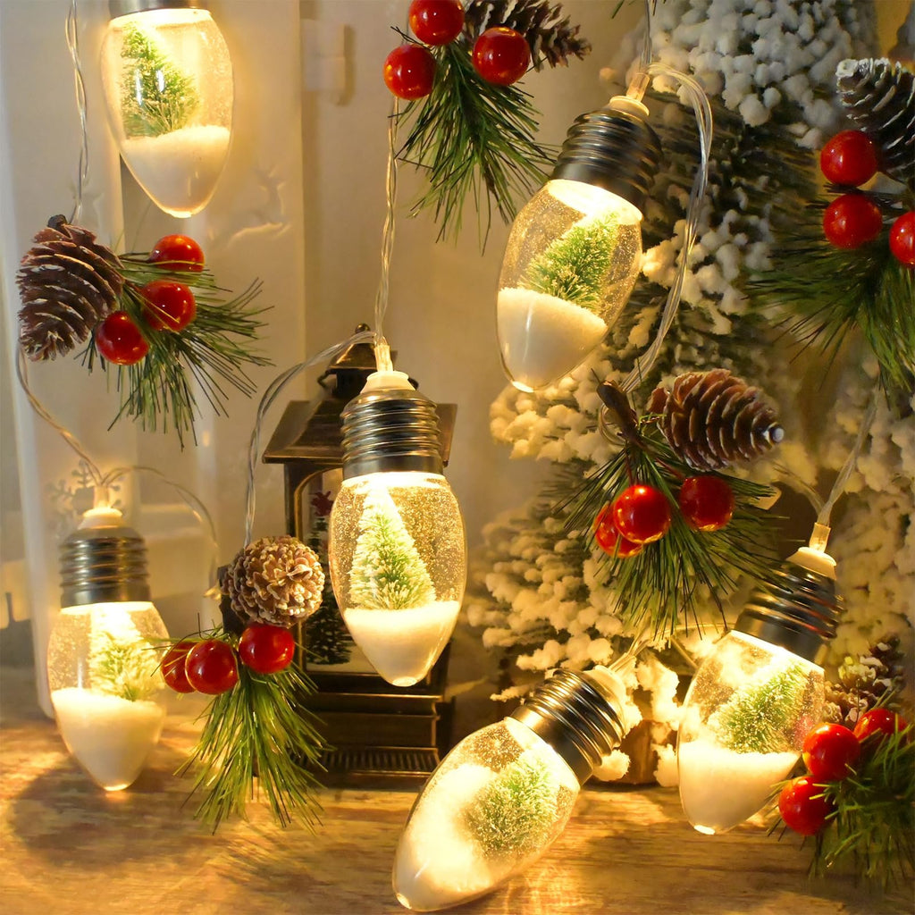 Christmas string lights with clear bulbs containing miniature snow-covered trees and pine sprigs with red berries