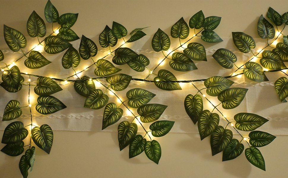 Green vine garland with 96 LED lights draped across a wall with a white textured fabric.