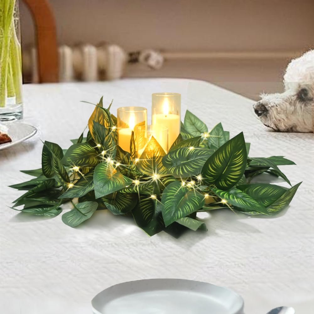 Green vine garland with three LED candles and fairy lights on a table, with a dog in the background.