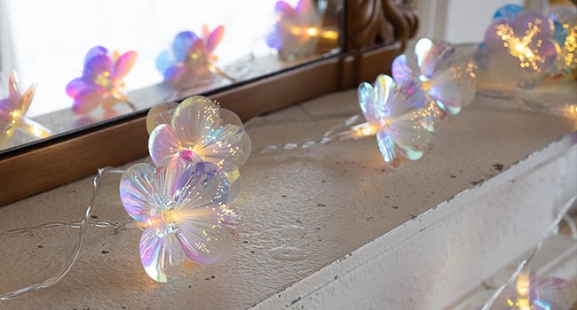 Fiber optic flower string lights with warm white LEDs arranged on a textured surface, reflected in a mirror.