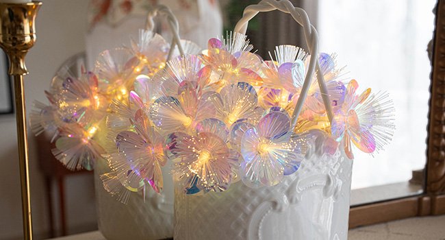 Fiber optic flower string lights with warm white LEDs arranged in a white basket.