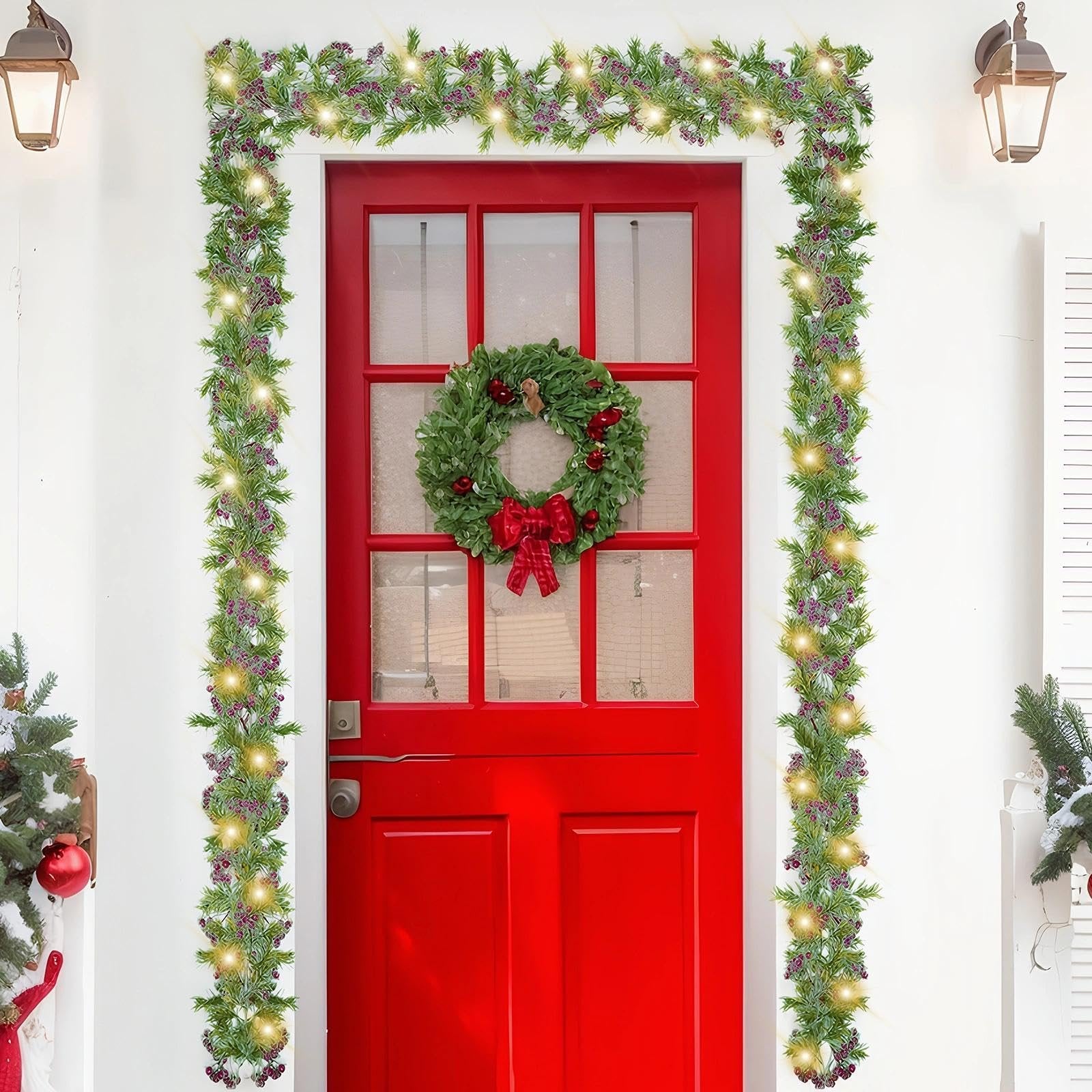 Christmas garland with warm white LED lights and red berries draped around a red door with a wreath